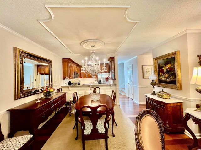 dining space with a textured ceiling, an inviting chandelier, dark hardwood / wood-style flooring, and crown molding