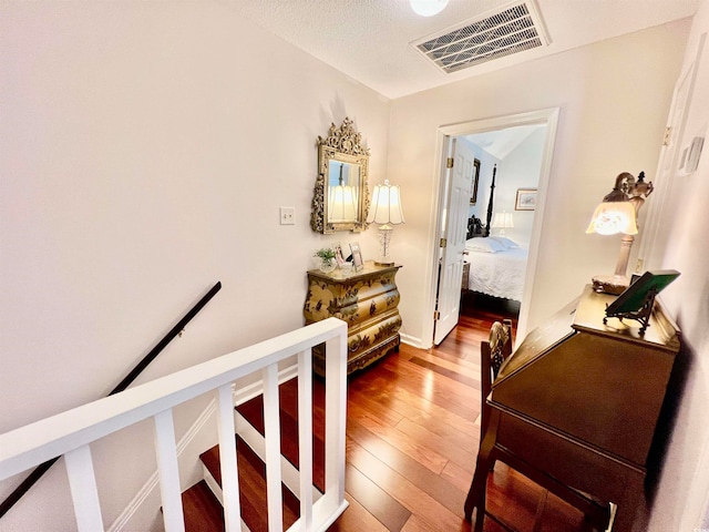 hallway with hardwood / wood-style floors and a textured ceiling