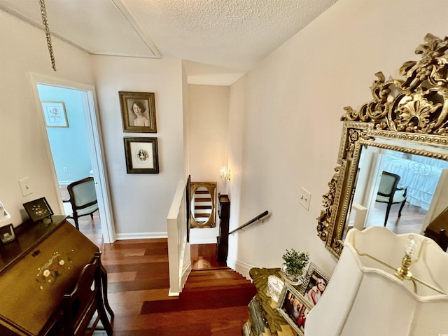 sitting room with baseboards, dark wood finished floors, a textured ceiling, and an upstairs landing