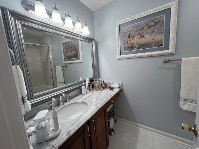 full bath featuring tile patterned floors, vanity, baseboards, and an enclosed shower