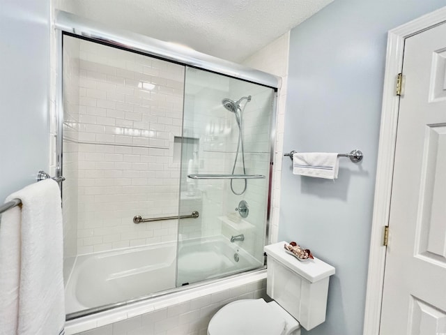 bathroom featuring toilet, combined bath / shower with glass door, and a textured ceiling