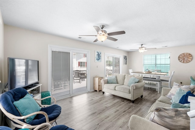 living room featuring ceiling fan, a textured ceiling, and light hardwood / wood-style floors