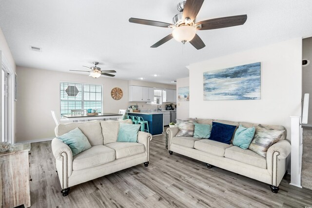 living room with ceiling fan, sink, and light hardwood / wood-style floors