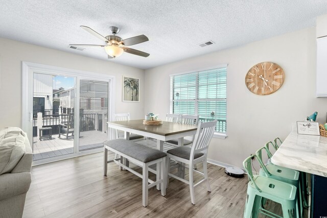 dining area featuring a textured ceiling, ceiling fan, and light hardwood / wood-style floors