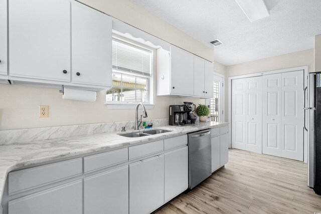 kitchen with white cabinetry, light stone countertops, light wood-type flooring, stainless steel appliances, and sink