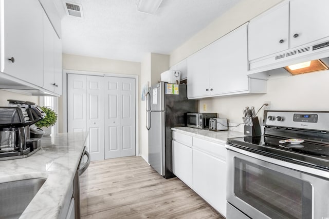 kitchen with appliances with stainless steel finishes, white cabinetry, light stone counters, a textured ceiling, and light wood-type flooring