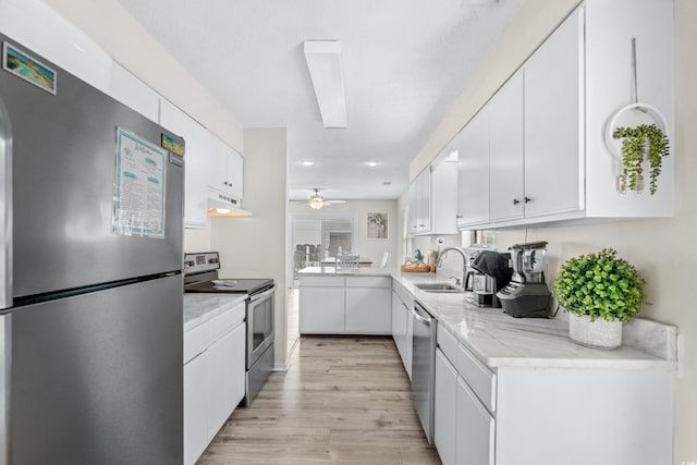 kitchen featuring stainless steel appliances, light hardwood / wood-style floors, sink, ceiling fan, and white cabinets