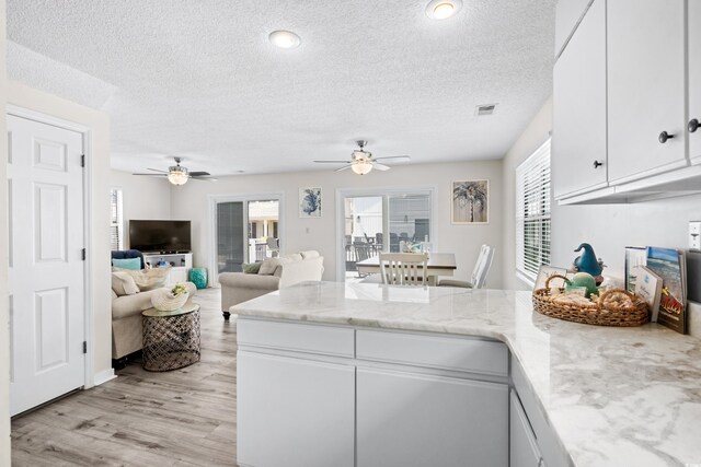 kitchen featuring light hardwood / wood-style floors, white cabinetry, ceiling fan, and a wealth of natural light