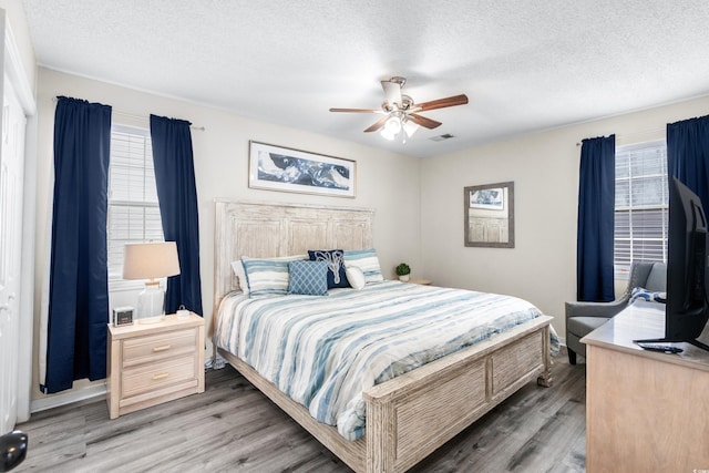 bedroom with ceiling fan, a textured ceiling, and dark hardwood / wood-style flooring