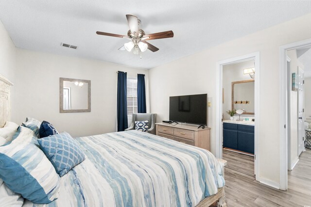 bedroom with ceiling fan, ensuite bath, and light hardwood / wood-style floors