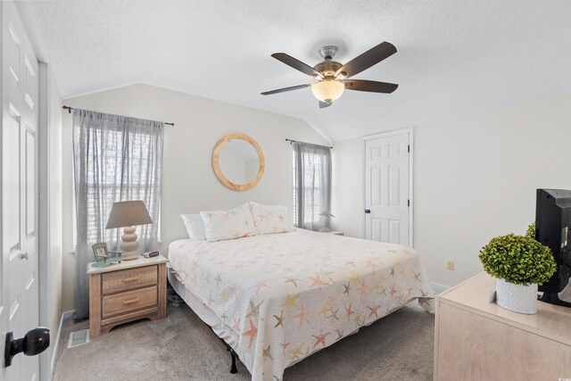 carpeted bedroom with ceiling fan, a textured ceiling, and vaulted ceiling