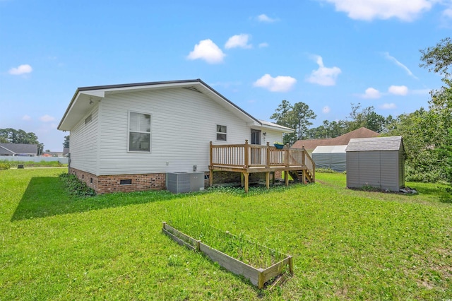 rear view of property featuring a vegetable garden, central air condition unit, crawl space, a shed, and an outdoor structure