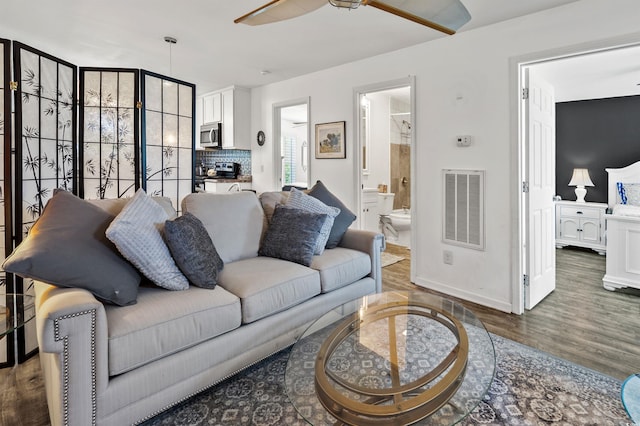 living room with ceiling fan and dark wood-type flooring