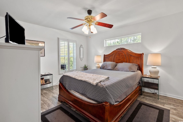 bedroom with multiple windows, baseboards, and wood finished floors