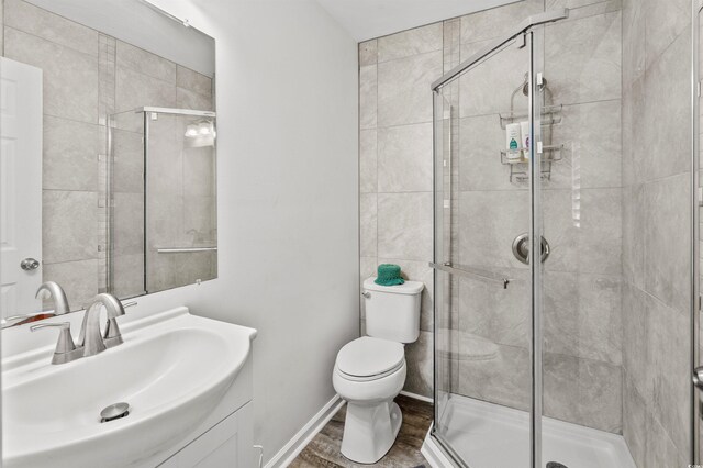 bathroom featuring hardwood / wood-style flooring, a shower with shower door, vanity, and toilet