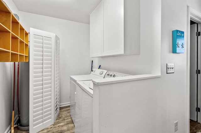 clothes washing area featuring cabinet space, wood finished floors, and washing machine and clothes dryer