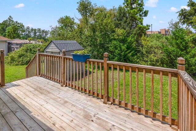 wooden deck with a storage shed and a lawn