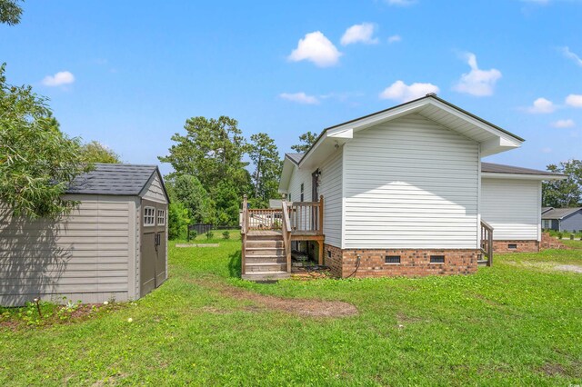 view of side of home featuring a wooden deck, a shed, and a yard