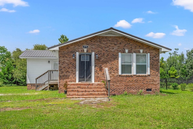 view of front of property featuring metal roof, brick siding, fence, crawl space, and a front yard