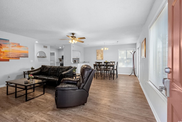 living room featuring a textured ceiling, hardwood / wood-style flooring, and ceiling fan with notable chandelier