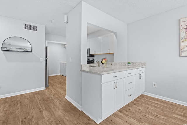 kitchen featuring white cabinetry, light hardwood / wood-style floors, and a textured ceiling