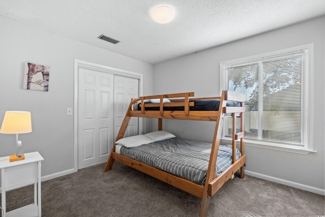 carpeted bedroom featuring a textured ceiling and a closet