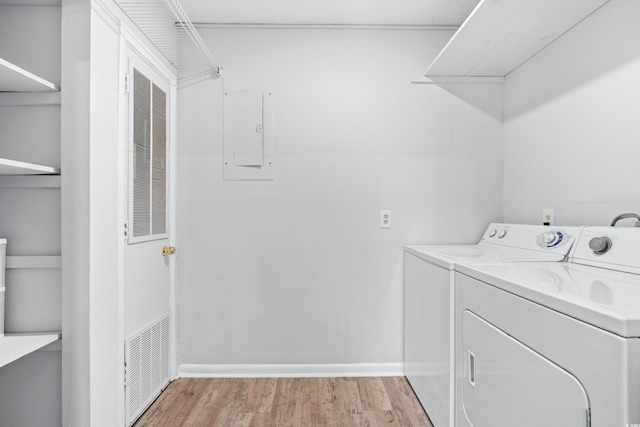 laundry room featuring washing machine and dryer, electric panel, and light wood-type flooring