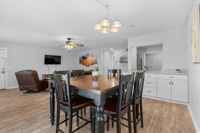 dining space with light hardwood / wood-style flooring and ceiling fan with notable chandelier