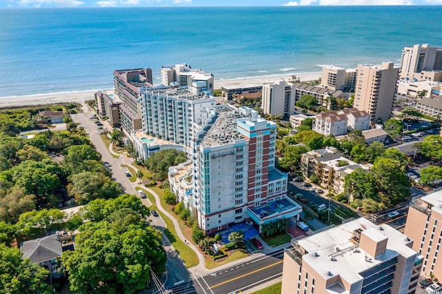 drone / aerial view featuring a city view, a view of the beach, and a water view