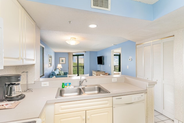 kitchen featuring dishwasher, sink, a textured ceiling, and kitchen peninsula