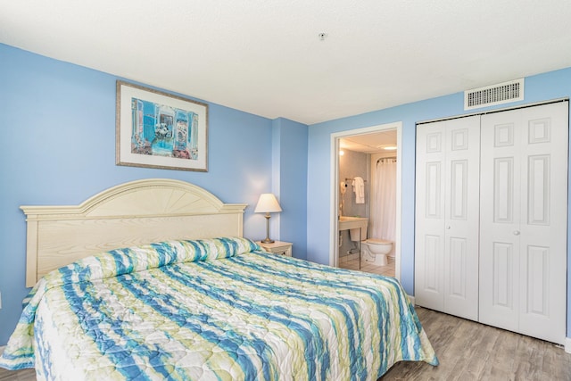 bedroom featuring ensuite bathroom, light hardwood / wood-style flooring, and a closet