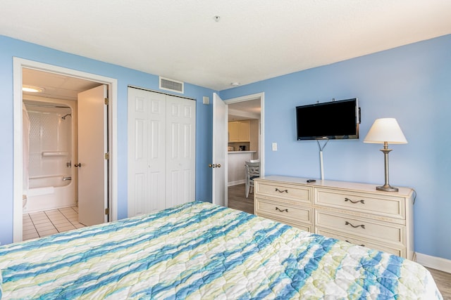 bedroom with connected bathroom, light hardwood / wood-style flooring, and a closet