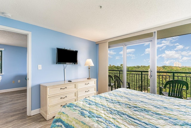 bedroom featuring access to exterior, a textured ceiling, and light hardwood / wood-style floors