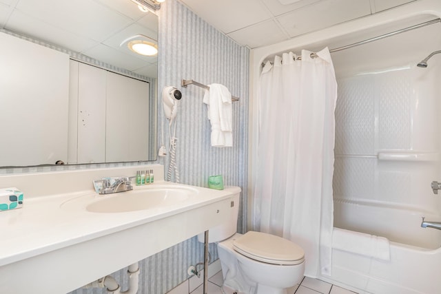 full bathroom featuring a drop ceiling, toilet, shower / tub combo, tile patterned floors, and sink