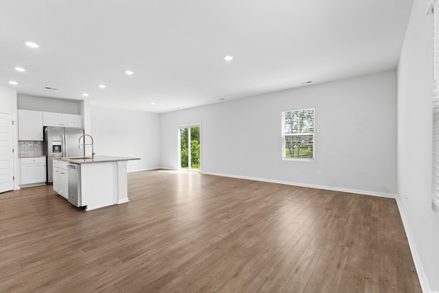 unfurnished living room featuring wood-type flooring and sink