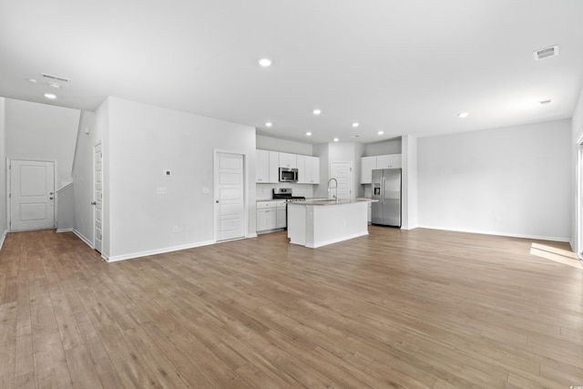 unfurnished living room with light hardwood / wood-style floors and sink