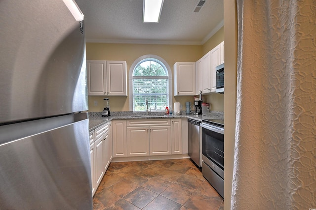 kitchen with dark tile patterned flooring, stainless steel appliances, light stone countertops, ornamental molding, and sink