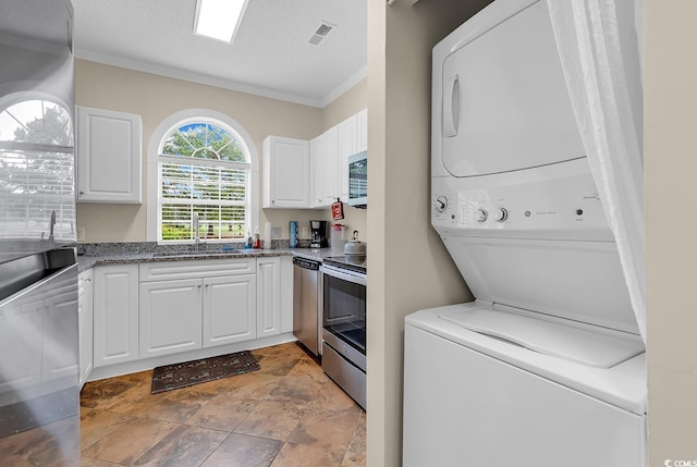 4709 Wild Iris Dr Unit 104, Myrtle Beach, SC 29577 - laundry room featuring estacked washer and dryer, crown molding, stone finish floors, and a textured ceiling