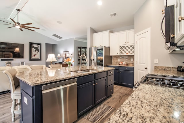 kitchen with appliances with stainless steel finishes, white cabinetry, sink, a breakfast bar area, and a center island with sink