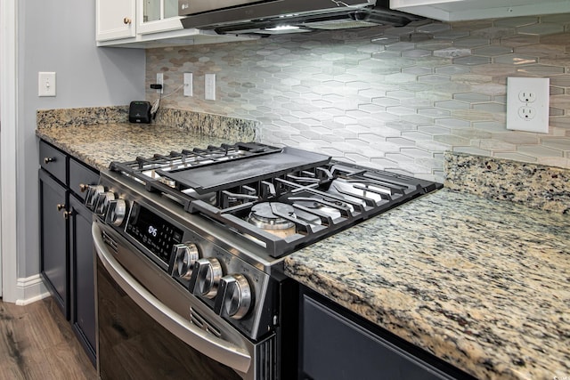 kitchen with stone counters, dark hardwood / wood-style floors, tasteful backsplash, white cabinetry, and stainless steel gas range oven