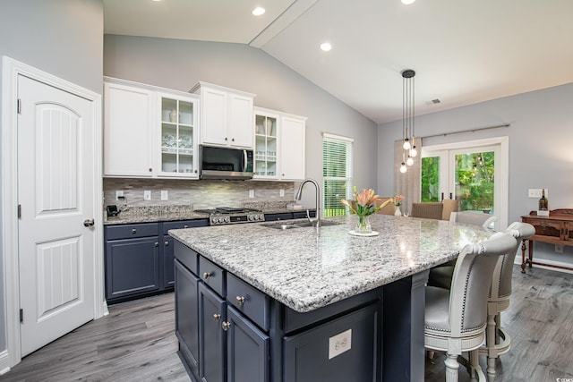 kitchen with white cabinetry, blue cabinetry, sink, and a kitchen island with sink