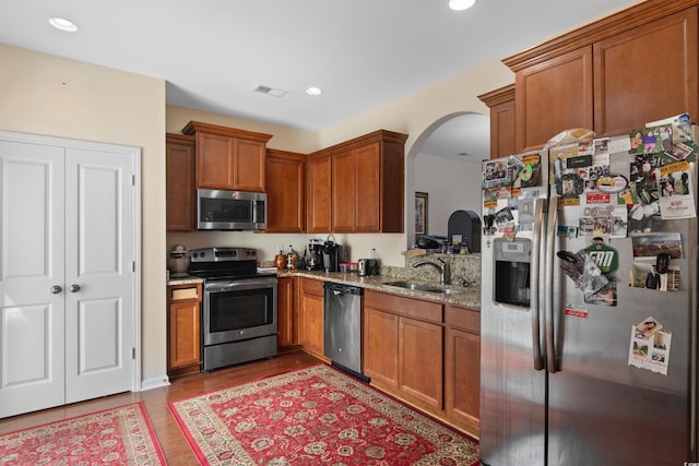 444 Papyrus Cir Unit 444, Little River, SC 29566 - kitchen with stainless steel appliances, arched walkways, light stone countertops, brown cabinetry, and recessed lighting