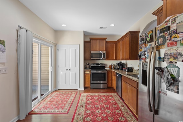 444 Papyrus Cir Unit 444, Little River, SC 29566 - kitchen with appliances with stainless steel finishes, light stone counters, brown cabinetry, wood finished floors, and plenty of natural light