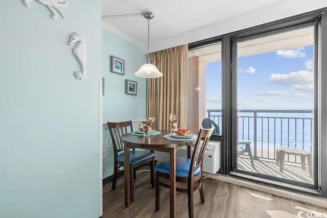 dining room with a water view, wood-type flooring, and crown molding