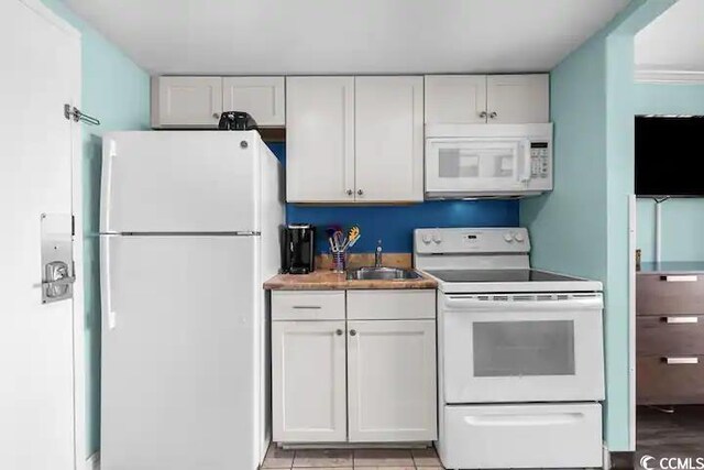 kitchen with white appliances, sink, light wood-type flooring, and white cabinetry