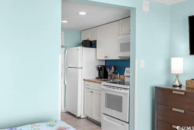 kitchen with white cabinetry, white appliances, and light tile patterned flooring