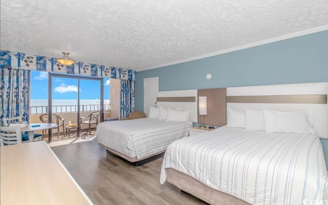 bedroom featuring a water view, hardwood / wood-style flooring, crown molding, and a textured ceiling