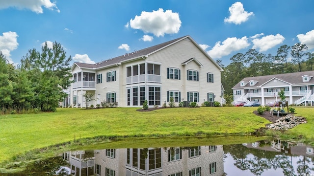 back of house with a water view and a lawn