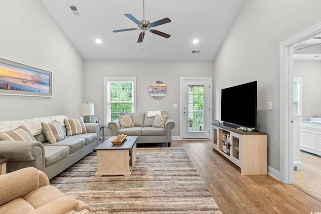 living room with ceiling fan, high vaulted ceiling, and light wood-type flooring