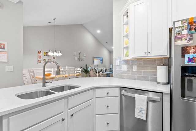 kitchen with decorative backsplash, lofted ceiling, appliances with stainless steel finishes, white cabinets, and sink